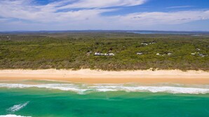 Il s'agit d'une zone côtière avec une plage et une colline boisée. On y trouve plusieurs bâtiments, probablement des éléments d'un complexe hôtelier ou d'une propriété de vacances.