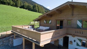 A wooden chalet with a balcony, a sofa, and a small table. - Kitz-Chalet - Luxury Chalet in Kitzbühel (Kitzbühel)