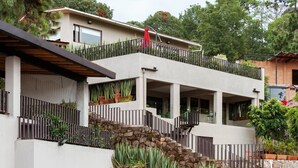 Una casa moderna de dos pisos con un balcón, escalones de piedra y un jardín.