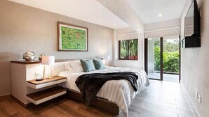 Un dormitorio moderno con cama, mesita de noche y un ventanal con vistas a zonas verdes.