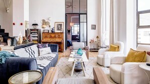 A spacious living room with a sofa, armchairs, a coffee table, and a piano.