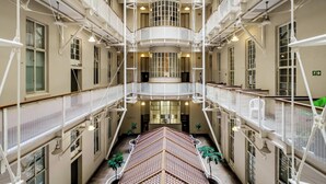 A multi-level atrium with a central staircase, balconies, and potted plants.