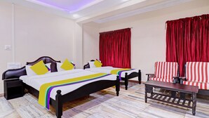 Una habitación de hotel con dos camas, una mesita y cortinas rojas.