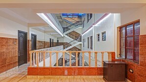 Un interior de varios niveles con una escalera central, piso de mármol y barandilla de madera.