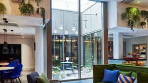 A modern interior with a green sofa, blue chairs, a coffee table, and a dining area.