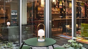 A modern outdoor seating area with a round table and chairs, surrounded by potted plants.