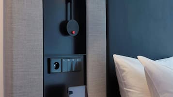 A modern room with a black desk, a red chair, a white pillow, and a black lamp.
