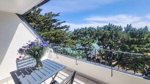 Een balkon met een metalen hekwerk, een tafel en een vaas met bloemen.