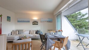 Een gezellige zithoek met een bank, een eettafel gedekt voor twee personen en een balkon met een hekwerk.