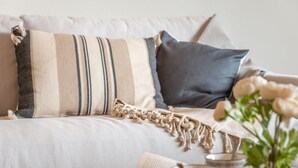 Een gezellige woonkamer met een bank, een gestreept kussen en een macramé plaid.