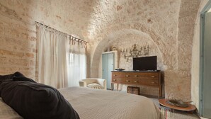 Une chambre à coucher avec un grand lit, une commode, une chaise et un téléviseur posé sur la commode.