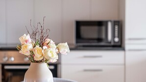 Eine weiße Vase mit Blumen auf einem runden Tisch in einer modernen Küche.