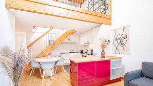 Eine moderne Küche mit weißen Schränken, einer roten Kochinsel und einer Holztreppe.