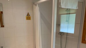 A shower room with a glass door, a white sink, and a wooden floor. - Log cabin with veranda, nestled in Kenwick Park, Louth (Louth)