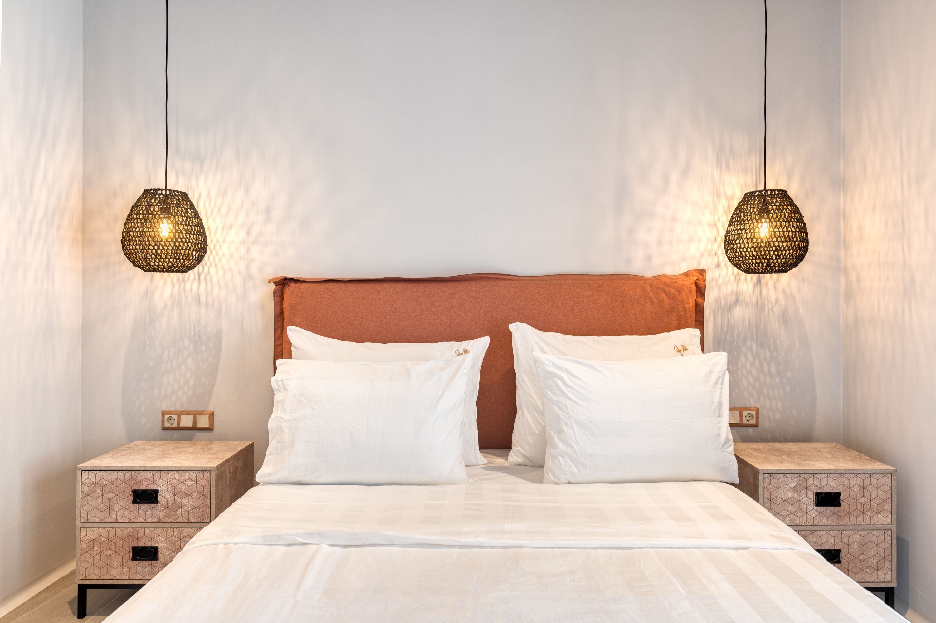 A neatly made bed with two pillows, a headboard, and two bedside tables with drawers.
