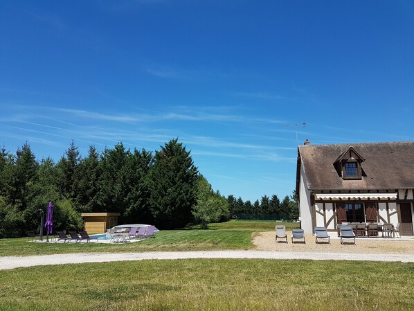 A house with a sloped roof, a small attic window, and a gravel driveway.