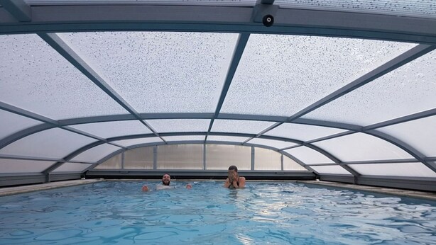 An indoor swimming pool with a glass ceiling and metal beams.