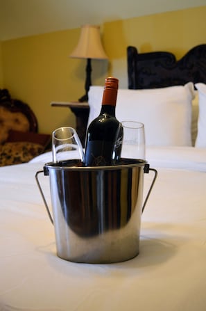 A metal bucket with a bottle and two glasses on a bed. - Magnetic Hill Winery (Moncton)