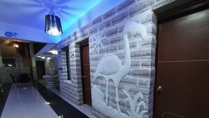 A hallway with a stone wall mural of a flamingo, a door, and a hanging light fixture.