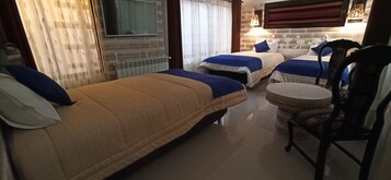 Habitación de hotel con dos camas, una mesa redonda y un televisor.