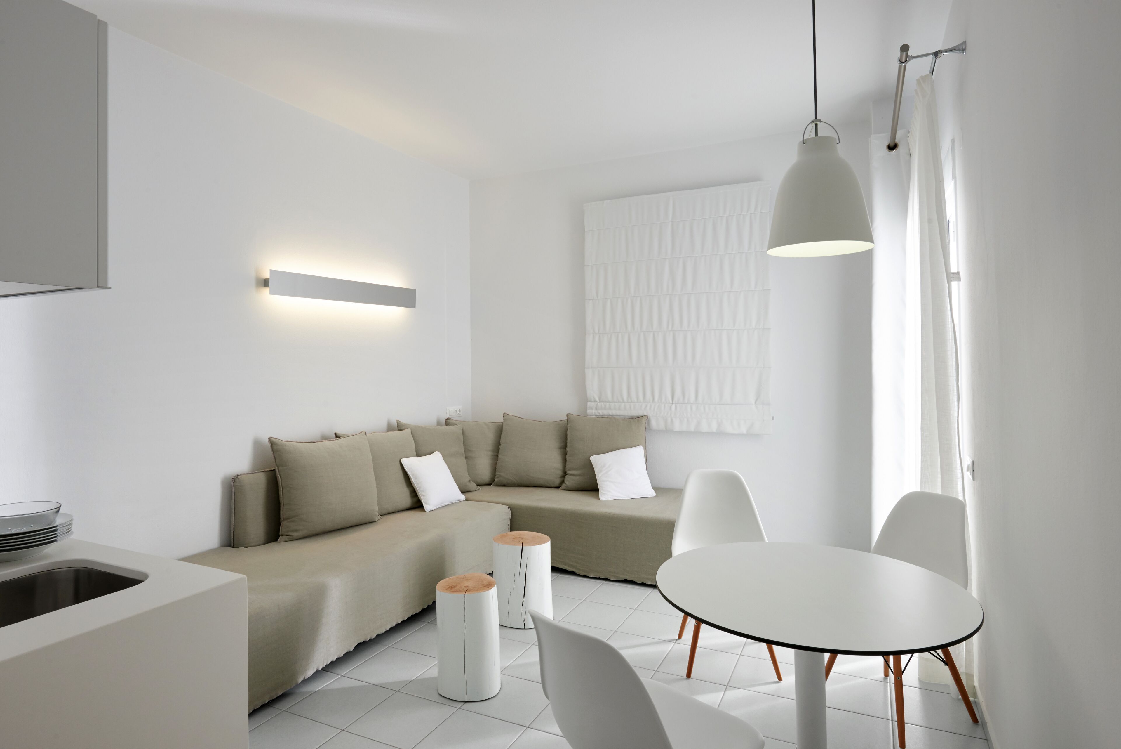Una sala moderna con un sofá, una mesa de comedor y dos mesas auxiliares.