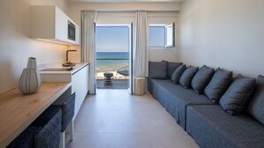 A modern, compact room with a sofa, a dining area, and a view of the sea. - Akrogiali Beach Hotel Apartments (Hersonissos)
