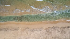 An aerial view of a beach with clear water, a sandy shore, and gentle waves. - Akrogiali Beach Hotel Apartments (Hersonissos)