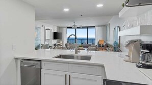 Una cocina moderna con una isla grande, lavavajillas integrado y una cafetera.