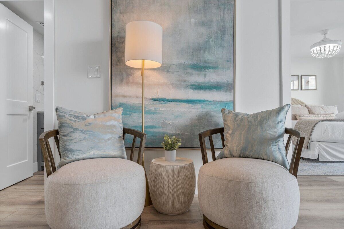 A modern living room with two round ottomans, a floor lamp, and a large abstract painting on the wall.