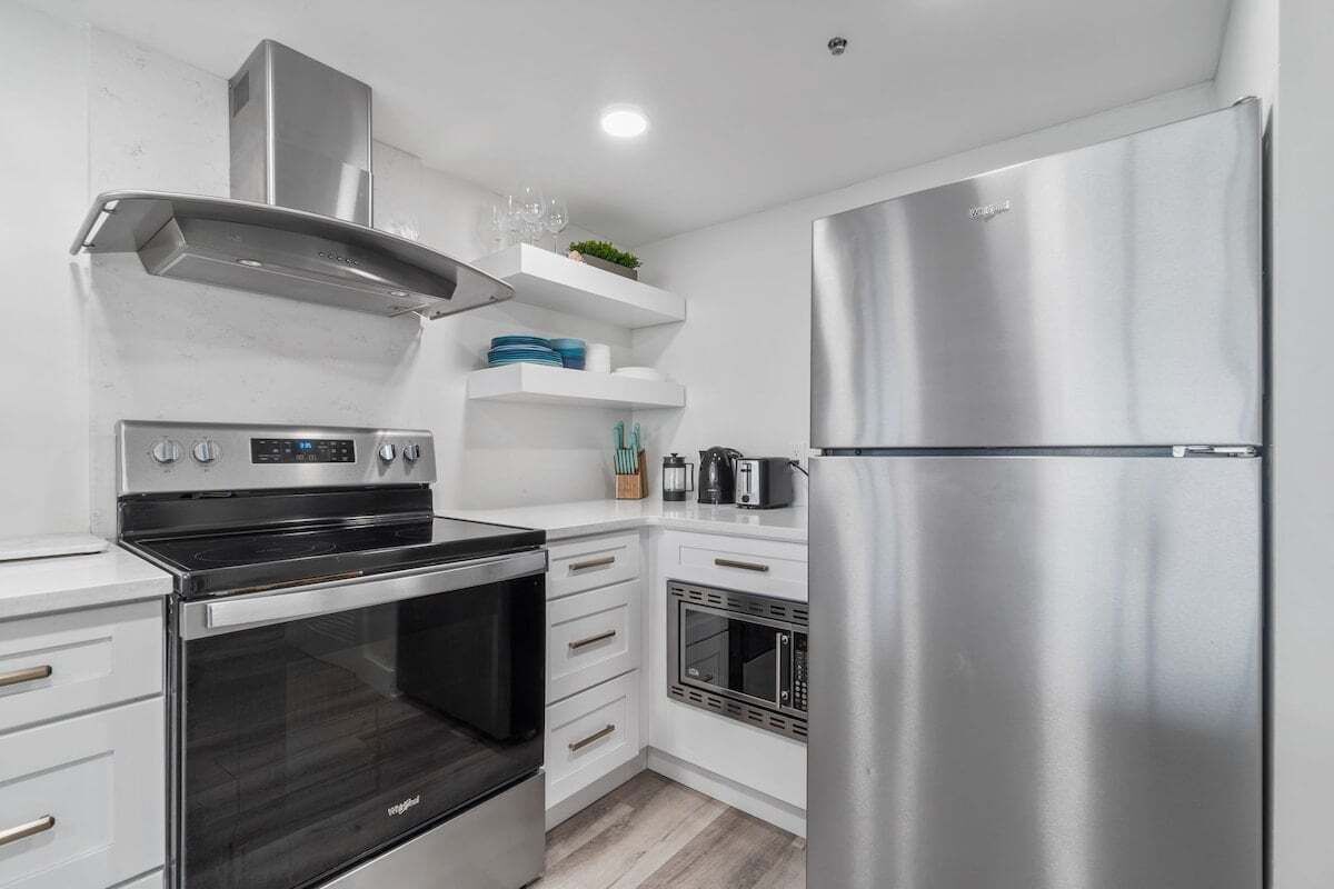A modern kitchen with stainless steel appliances, white cabinetry, and a built-in oven.