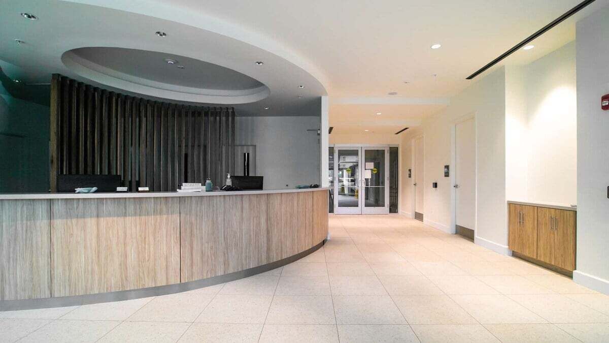 A modern reception area with a curved reception desk, a flat-screen TV, and a wooden panel wall.