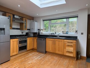 Una cocina moderna con armarios de madera, electrodomésticos de acero inoxidable, un tragaluz y vistas al exterior.