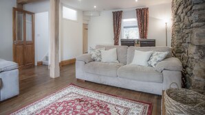 A cozy living room with a sofa, a patterned rug, and a stone wall.