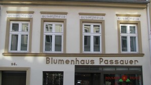 Un bâtiment avec trois fenêtres et une enseigne sur laquelle on peut lire « Blumenhaus Passauer ».