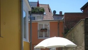 Une terrasse avec une table et des chaises, un parasol et un mur en briques.