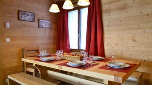 Una mesa de comedor de madera dispuesta con platos, vasos y una cesta de fruta.