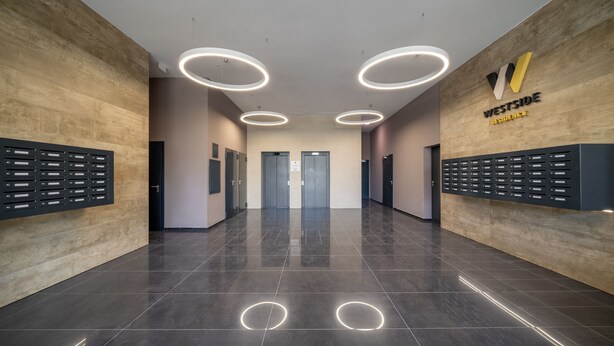 A modern hallway with a wooden wall, a reception desk, and a sign for 'Westside Residence'. - WestSide Apartments by FirstHost (Budapest)