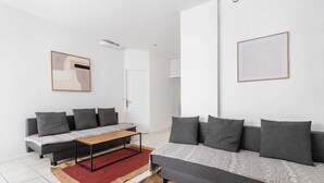 Un salon moderne avec un canapé gris, une table basse en bois et un tapis rouge.