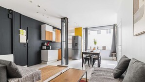 Un salon moderne comprenant un canapé, une table basse et un coin repas avec une table et des chaises.