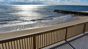 Ein Strand mit einer Holzpromenade und einem steinernen Wellenbrecher.