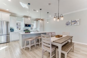Una cocina moderna con armarios blancos, una isla central e iluminación colgante.