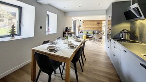 Una cucina moderna con forno integrato e microonde, un'area pranzo con tavolo e sedie in legno e vista sul giardino attraverso ampie finestre.