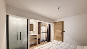 Una camera da letto con un letto, un armadio, uno specchio, un lavandino e una porta.