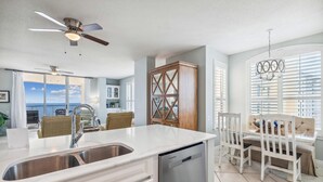 Une cuisine moderne dotée d’un grand îlot central, d’un ventilateur de plafond et offrant une vue sur l’océan.