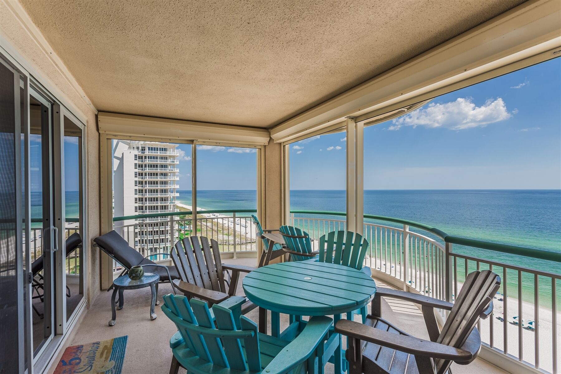 A covered balcony with a view of the ocean, featuring a table and chairs.