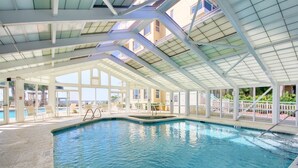 Ein Innenpool mit klaren Glasswänden, gefliestem Boden und einer Poolleiter.