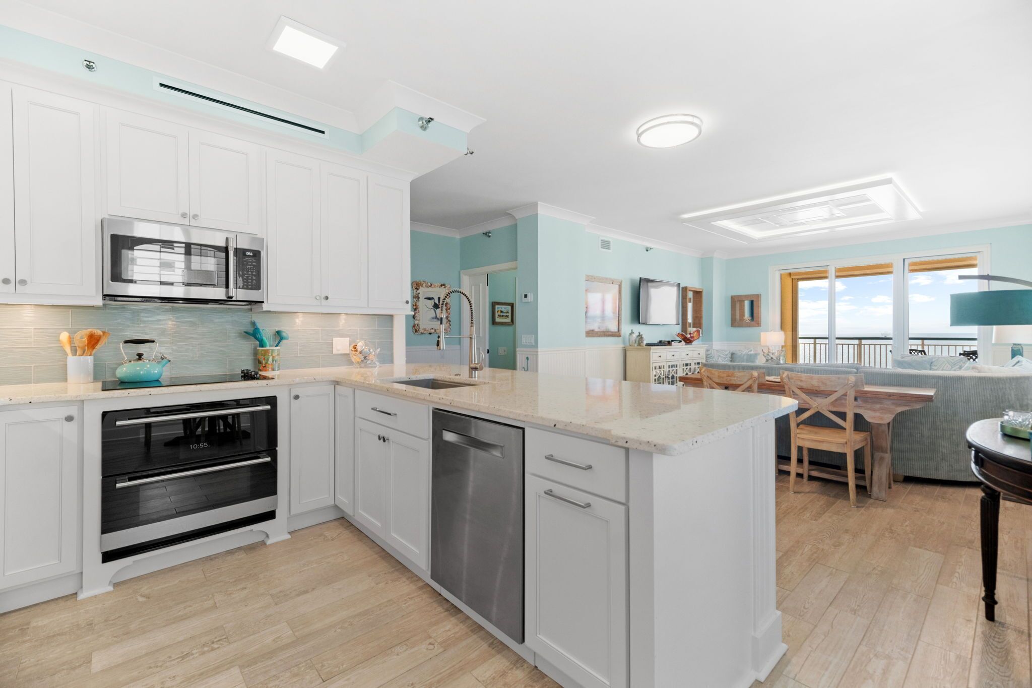 A modern kitchen with white cabinetry, stainless steel appliances, and a light blue accent wall.
