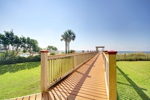 A wooden deck leading to a beach with a clear sky.