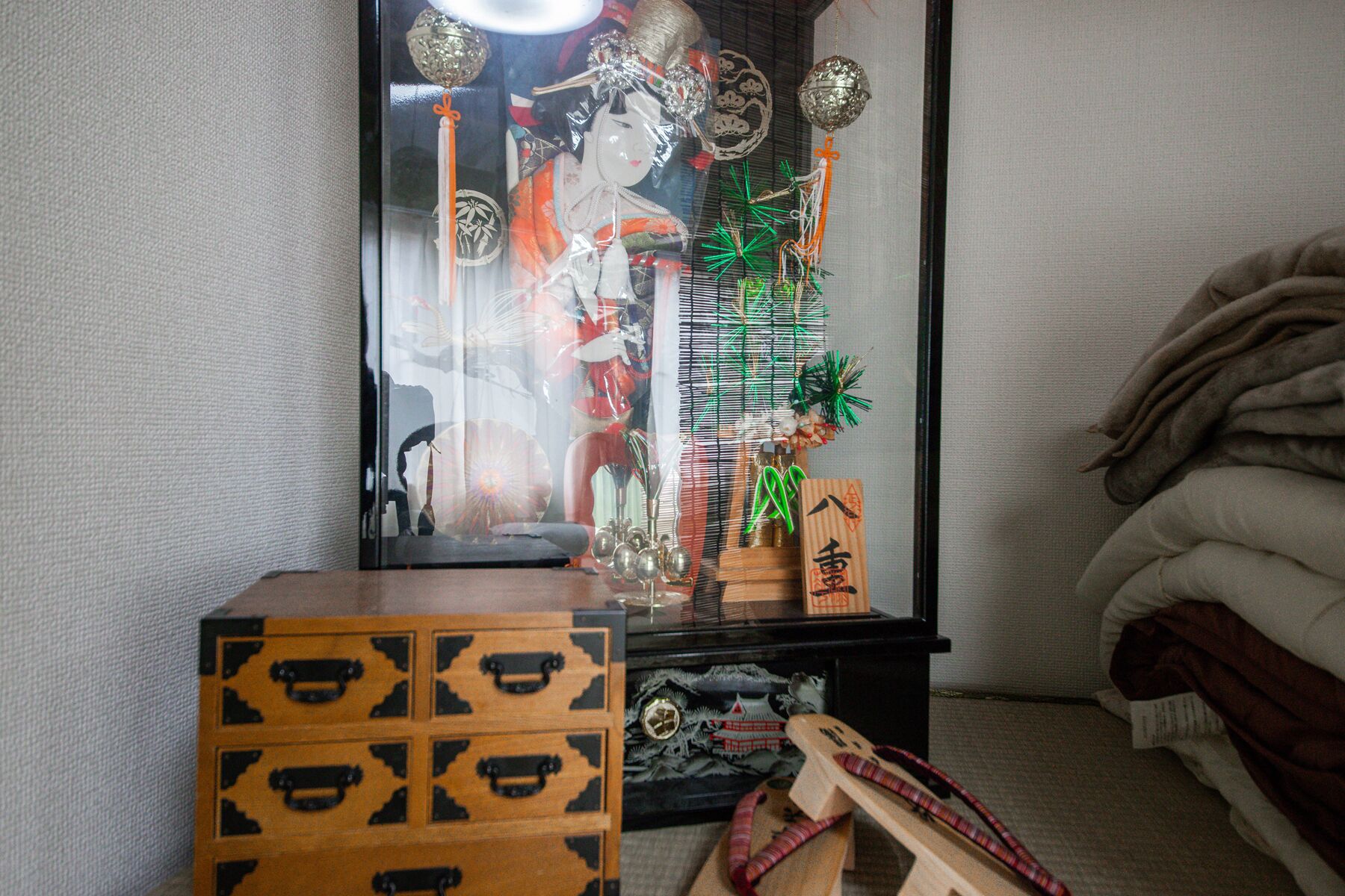 A room with a traditional Japanese altar, a wooden chest, and a futon bed.