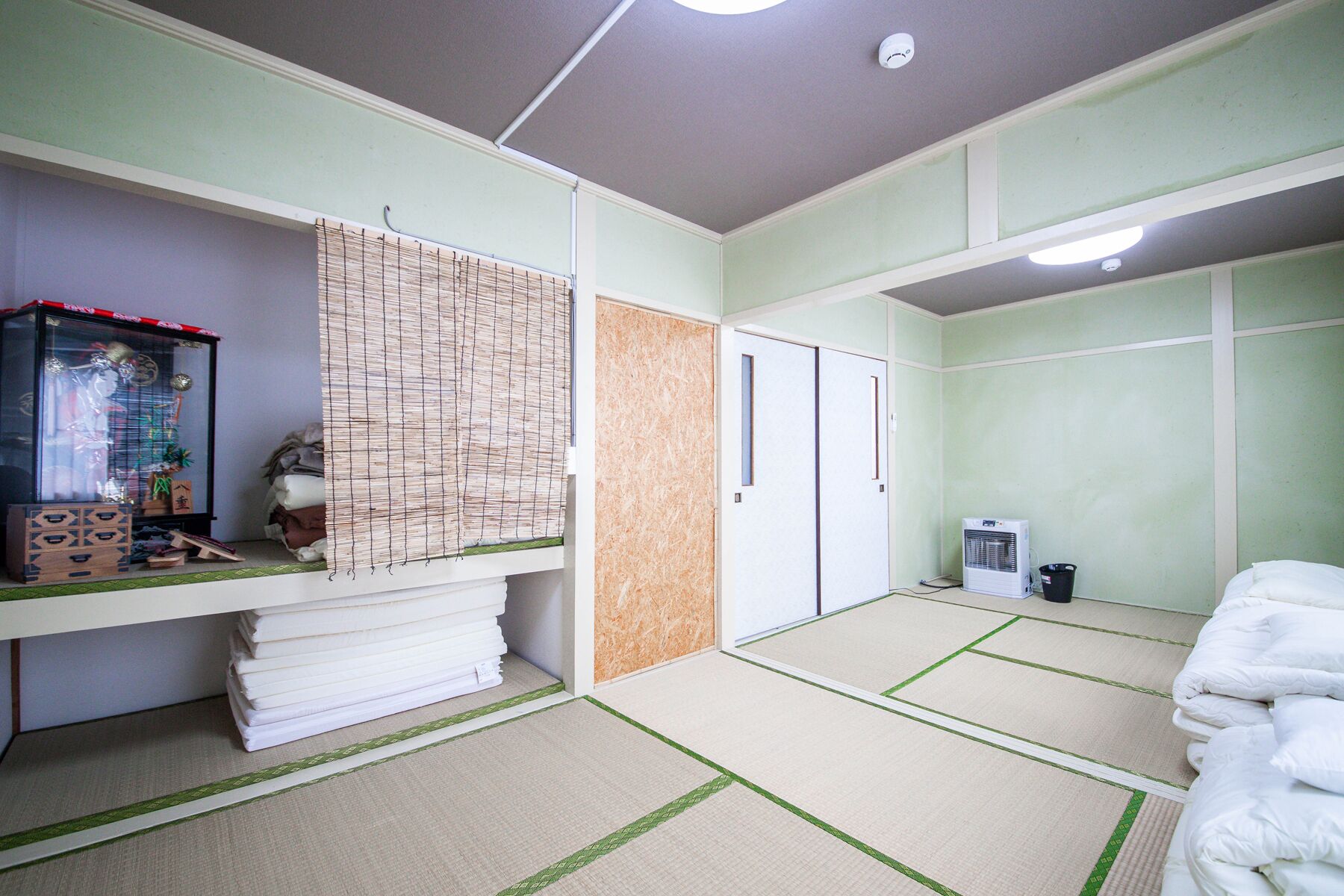 A room with tatami mats, a traditional Japanese-style room, a heater, and a cabinet with various items.